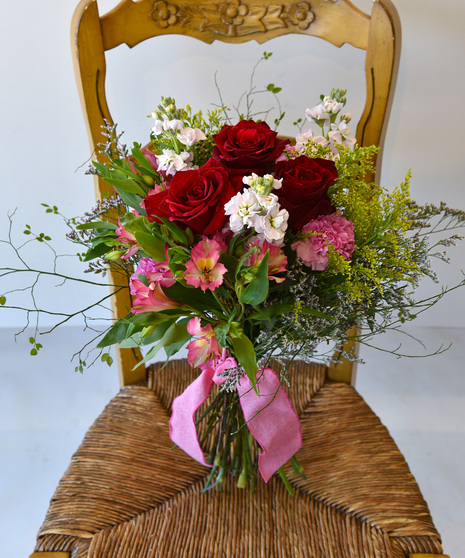 A  hand-tied bouquet of  blooms in shades of blush pink mauve to raspberry red with seasonal foliage.