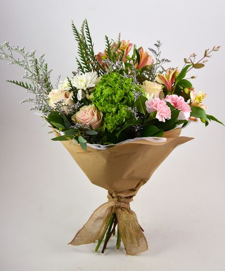 The pastel hand-tied bouquet with soft-hued blooms and foliage.  The vibrant hand-tie is a cheery composition of spirited blooms and foliage will brighten the day.