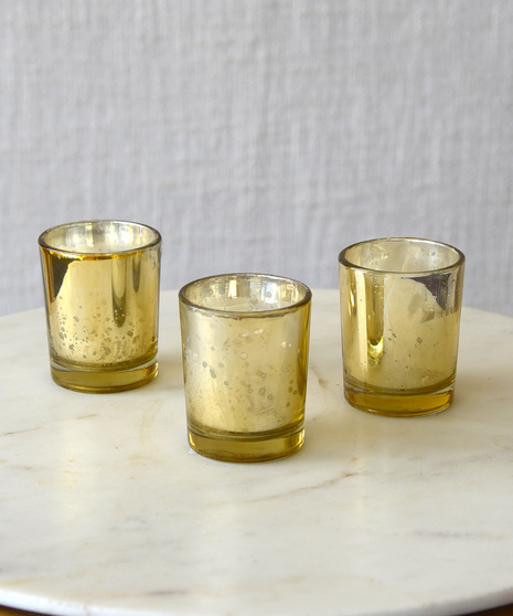 Celebrate Diwali with warm yellow and orange marigolds, accented with red roses, purple carnations designed in a antique gold glass compote that shimmers by candlelight