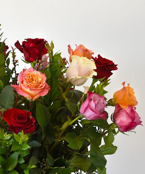 Dozen Luxury Mixed Roses in an array of complementary colors gathered in a tall glass vase. 