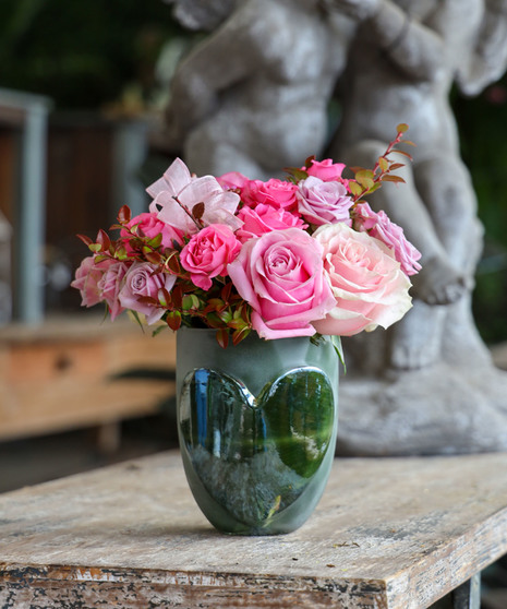 Blushing roses in pink and lavender classically designed in a leaf lined glass vase with an embossed heart