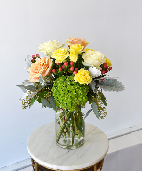 Rose Simplicity a lush and beautiful collection of premium roses, paired with delicate spray roses in buttercream yellow, blush peach and creamy white roses in glass vase. 