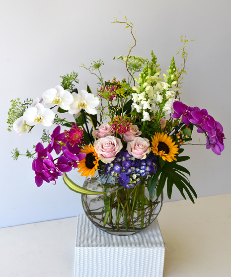 Designed in a sphere glass vase is a composition of vibrant colors of yellow, pinks and orange with the cooling of pastel white and blues. 