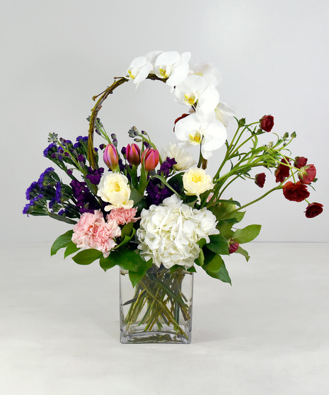 Stylish vase arrangement with a cheerful palette of tulips, roses, hydrangea and stock. 