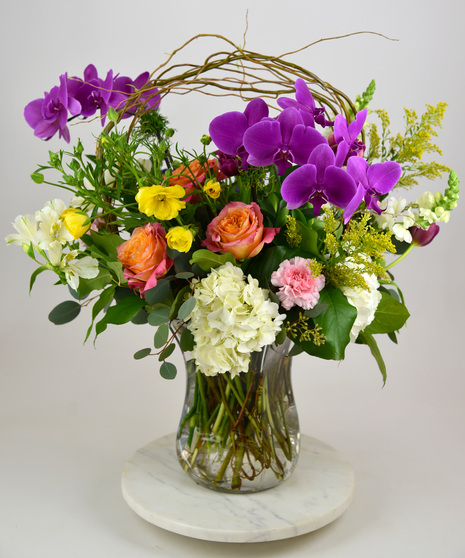 Stylish vase arrangement with a cheerful palette of tulips, roses, hydrangea and stock. 