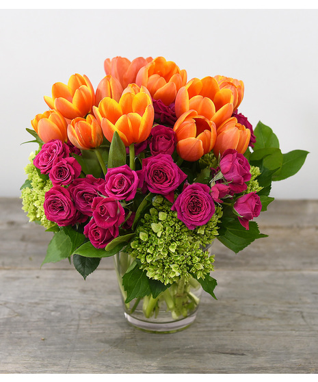 Cheerful tulips, spray roses, hydrangeas designed in a glass vase.