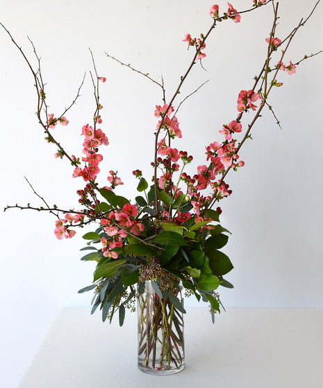 Blooming from bare branches, are an abundance of deep pink to red blossoms.  The Grand includes red gladiolas. Designed in glass vase.