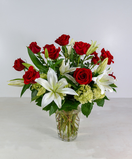 Premium Red Roses with fragrant liles and hydrangeas designed in a clear glass vase.  Upgrade to 24 roses