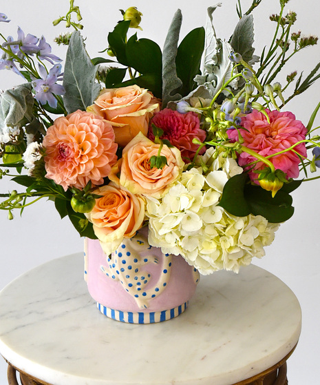 White with blue spot leopard on a pink vase filled with summer flowers