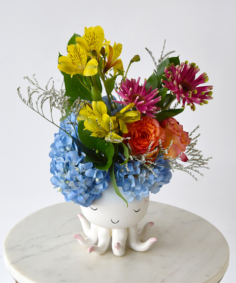 Close up view of the ceramic cream octopus with blue and pink accents with hydrangea, alstoremeria, roses, gerbera.