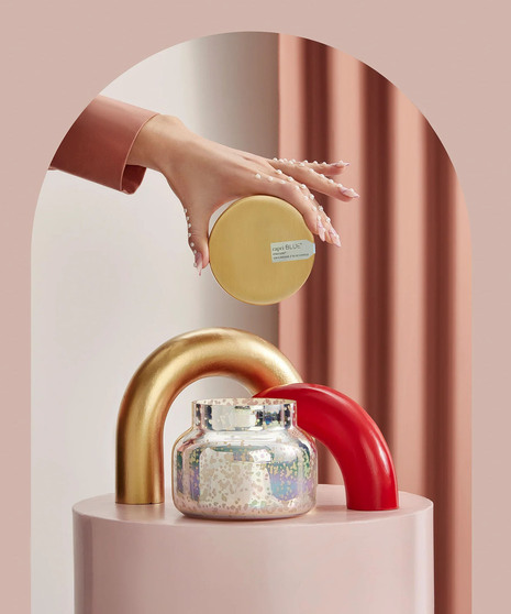 Iridescent candle with hand holding the gold colored cover.